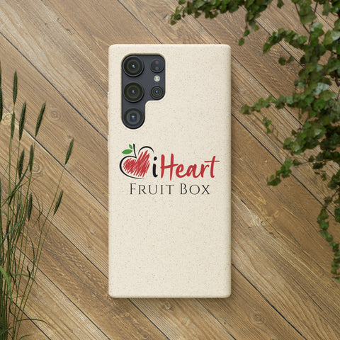 A white iHeartFruitBox Biodegradable Phone Case on a wood surface with a Printify sticker.