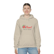 A woman wearing a beige iHeartFruitBox Unisex Heavy Blend™ Hoodie by Printify, holding an iHeartFruitBox.