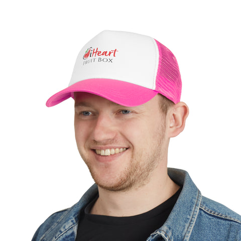 A man wearing a pink trucker hat and holding an iHeartFruitBox Branded Mesh Cap by Printify.