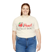 A woman smiling at camera with a Tropical Fruit in hand, showcasing the delicious and refreshing produce of Printify's iHeartFruitBox Fitted Unisex T-Shirts.