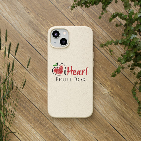 A white iHeartFruitBox Biodegradable Phone Case featuring a tropical fruit design, resting on a wood surface.