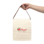 A hand holding a white iHeartFruitBox branded canvas lunch bag with strap filled with organically grown tropical fruit from Printify.