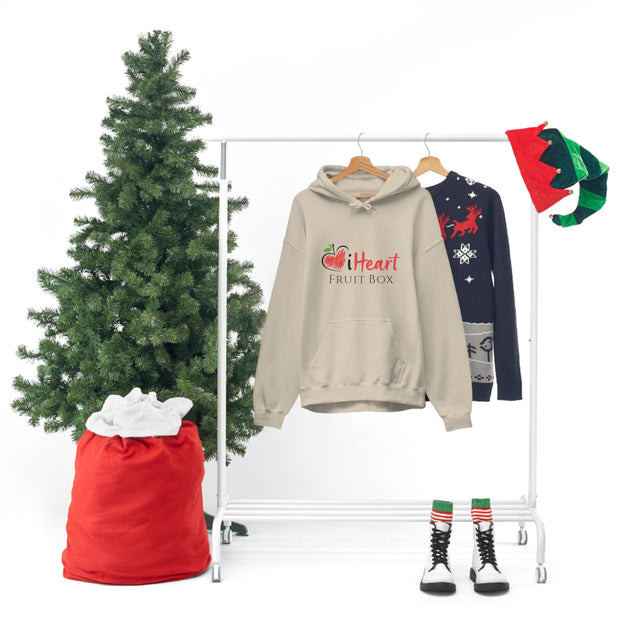 An iHeartFruitBox Unisex Heavy Blend™ Hoodie on a clothes rack adorned with Santa hats and sweaters. (Brand: Printify)