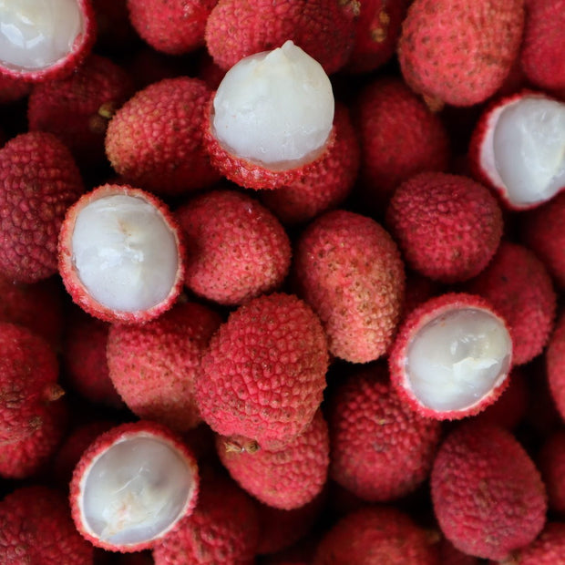 Close-up of fresh Lychee ***Pre-Order*** from sustainable farms, some peeled revealing white juicy flesh, surrounded by whole red textured skins by iHeartFruitBox.