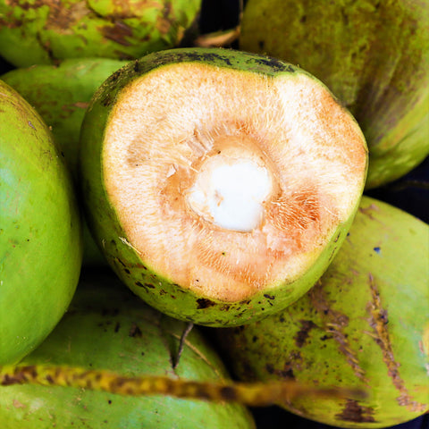 A pile of organically grown green iHeartFruitBox coconuts, a tropical fruit found in iHeartFruitBox.