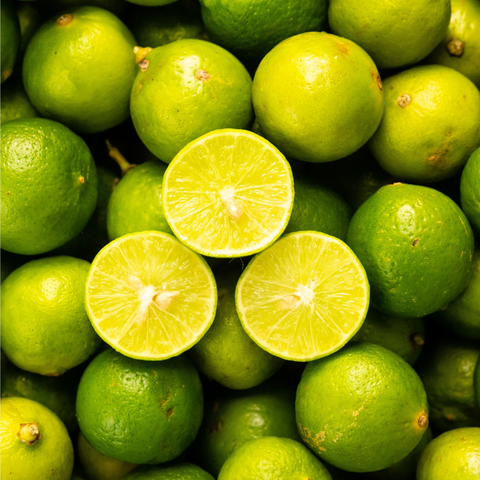 A group of Key Limes with one cut in half, arranged in an iHeartFruitBox.